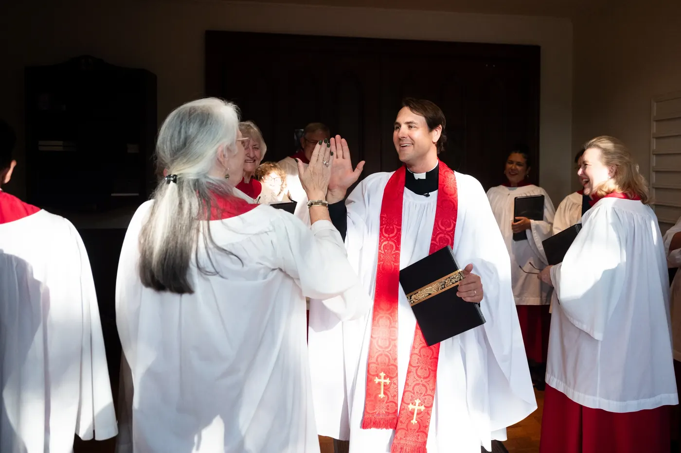 The rector high-fives a choir member as the choir gathers before a service.